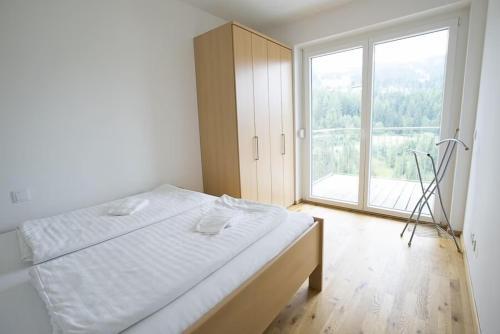 um quarto com uma cama e uma grande janela em Haus CKPK Lux em Sonnenalpe Nassfeld