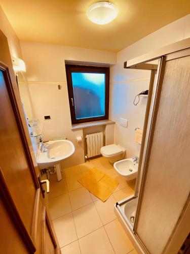 a bathroom with a sink and a toilet and a window at Apartments Residence Montana in Rasun di Sopra