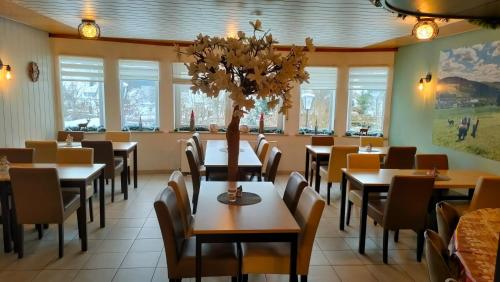 a dining room with tables and chairs and windows at Pension Sauerland in Winterberg
