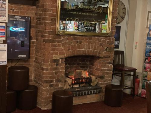 a brick fireplace with a fire in it at The Riverside in Sutton Bridge