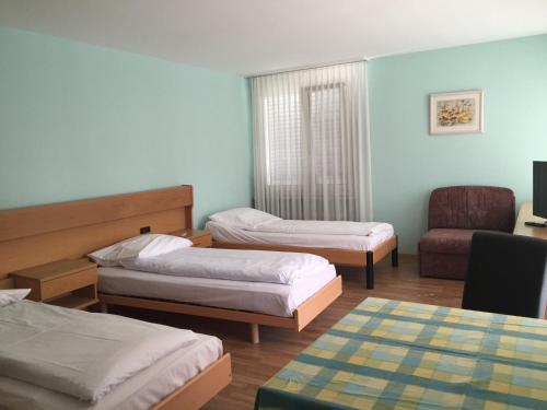 a hotel room with two beds and a chair at Hotel Mare & Monti in Bassersdorf