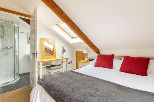 a bedroom with a bed with red pillows and a shower at Duke House - Top Floor Apartment - 1 bedroom apartment with Hot Tub in Padstow