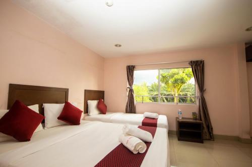 1 dormitorio con 2 camas con almohadas rojas y ventana en Sun Inns Hotel Bestari Jaya, en Batang Berjuntai