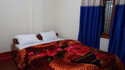 a bedroom with a bed with a blanket and flowers at HOTEL DENGCHEM Bomdila in Bomdila