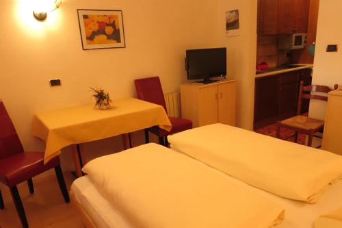 a room with two beds and a table and chairs at Apartments Residence Montana in Rasun di Sopra
