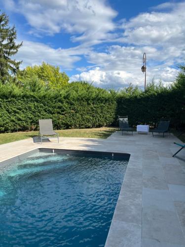 a swimming pool with two chairs sitting on a patio at Gite Lomegaja 6pers proche Lascaux et Sarlat in La Chapelle-Aubareil