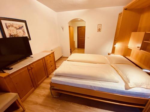 a bedroom with two beds and a flat screen tv at Apartments Residence Montana in Rasun di Sopra