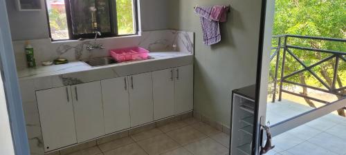 uma cozinha com armários brancos e um lavatório em firstrose villa 1 bedroom, new in Diani Beach, Kenya em Galu