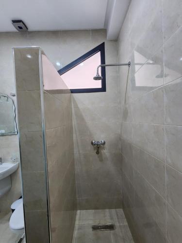 a bathroom with a shower with a window and a sink at فندق الشموخ Hotel Al Shmokh in Bir Gandouz