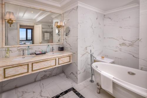 a white bathroom with a tub and a sink at Melia Vinpearl Tay Ninh in Tây Ninh