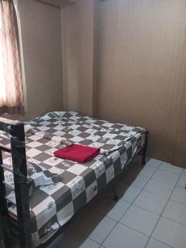 a bed with a black and white checkered blanket on it at Apartemen kalibata city by. Mataji in Jakarta