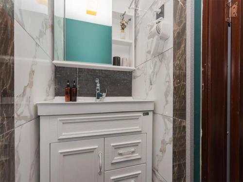 ein Badezimmer mit einem weißen Waschbecken und einem Spiegel in der Unterkunft Annie Apartment - only 120 metres from Metro Line 2 Exit B of Chuanxingulou in Kunming