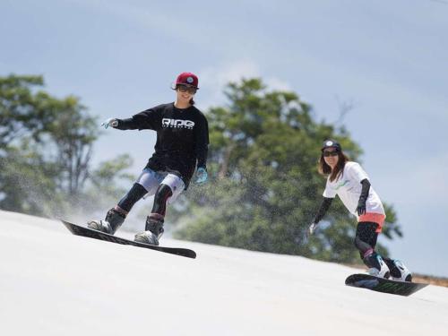 a man and woman snowboarding down a snow covered slope at Naeba Prince Hotel in Yuzawa