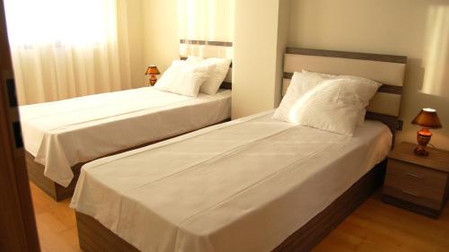 two beds in a bedroom with white sheets and pillows at Park Ej's Lake View Apartment A73 in Ohrid