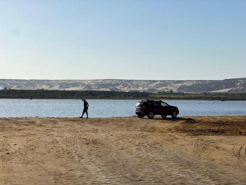 a man walking on a dirt road next to a car at Oasis Panorama Hotel in Bawiti