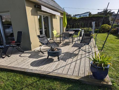 une terrasse en bois avec des chaises et un foyer extérieur dans l'établissement Plouguerneau - maison à 200 m de la mer, à Plouguerneau