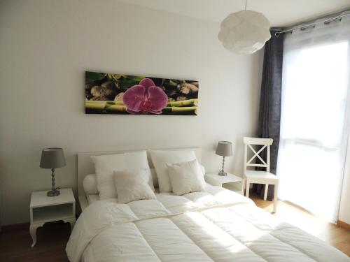 - une chambre dotée d'un lit blanc avec une fleur sur le mur dans l'établissement APPARTEMENT T2 MEUBLE AVEC BALCON TOULOUSE, à Toulouse