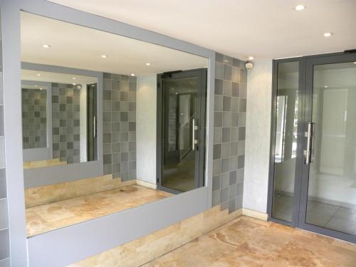 une rangée de miroirs dans une salle de bains avec du carrelage gris dans l'établissement APPARTEMENT T2 MEUBLE AVEC BALCON TOULOUSE, à Toulouse