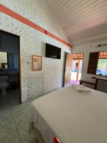 a bedroom with a white bed in a brick wall at Pousada Askalon in Itaúnas