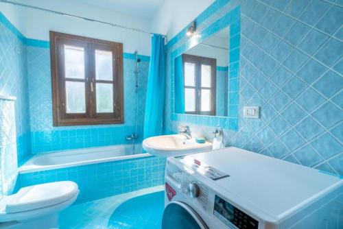 baño azul con lavabo, aseo y bañera en Appartamento Mountain View, en San Pantaleo