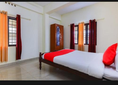 a bedroom with a bed with red sheets and windows at BENCH HOTEL VAGAMON in Vagamon