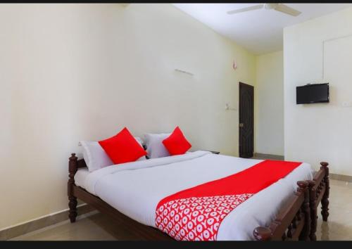 a bedroom with a large bed with red pillows at BENCH HOTEL VAGAMON in Vagamon