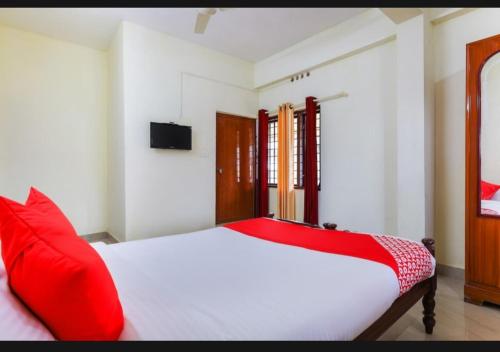 a bedroom with a white bed with red pillows at BENCH HOTEL VAGAMON in Vagamon