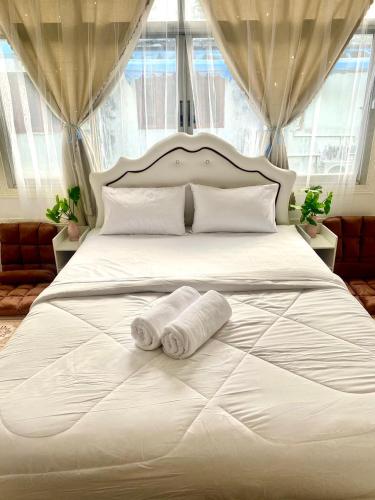 Una cama blanca con dos toallas enrolladas. en Guesthouse Station, en Bangkok