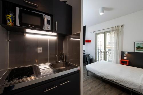 - une cuisine avec évier et un lit dans une chambre dans l'établissement Résilodge Lyon 2, à Lyon