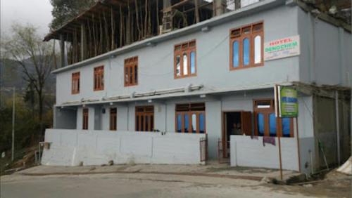 a large white building with red windows at HOTEL DENGCHEM Bomdila in Bomdila