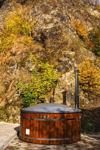 a wooden hot tub sitting in front of a mountain at Valea Mosului - Cozy A Frame in Petroşani