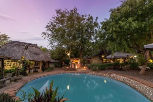una piscina frente a un complejo por la noche en Victoria Falls Backpackers Lodge en Victoria Falls