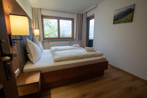a bedroom with a bed with a nightstand and a window at Hochtenn Lodge in Zell am See - Steinbock Lodges in Zell am See
