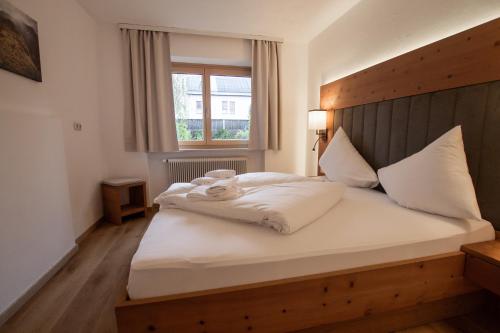 a bedroom with a bed with a wooden headboard and a window at Hochtenn Lodge in Zell am See - Steinbock Lodges in Zell am See