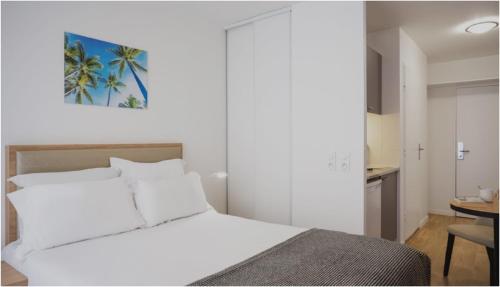 a bedroom with a white bed and a table at Séjours & Affaires Paris Bagnolet in Bagnolet