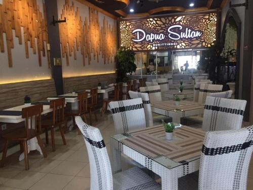 a dining room with tables and white chairs and a restaurant at Sultan Syariah Hotel in Bukittinggi