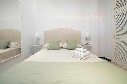 um quarto branco com uma cama com toalhas em AlohaMundi Lumbreras II em Sevilha