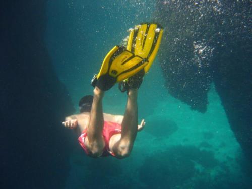 a man swimming in the water with a pair of shoes at La Petite Calanque in Marseille