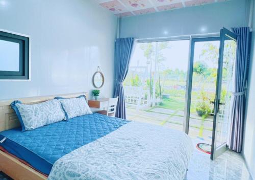 een slaapkamer met een blauw bed en een glazen schuifdeur bij Homestay Nguyễn Hưng in Tân Tạo