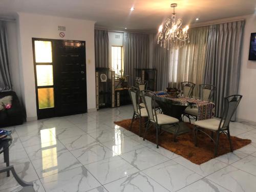 a dining room with a table and chairs and a chandelier at MajaK Guesthouse in Soweto