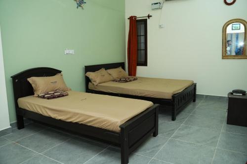two beds sitting in a room with a mirror at UNGA VEEDU PAY AND STAY in Tiruvannāmalai