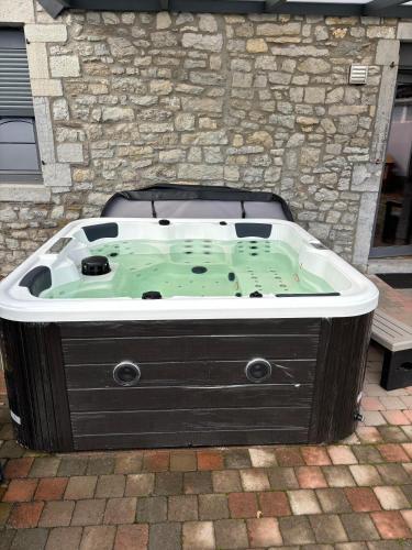 a hot tub in front of a stone building at La porte du paradis in La Roche Madoux