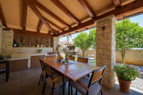 eine Außenküche und ein Esszimmer mit einem Holztisch und Stühlen in der Unterkunft Villa Clariss in Višnjan
