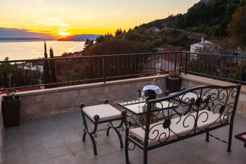 a balcony with a table and chairs and the sunset at 19th Century stone art house in NATURE PARK in Makarska
