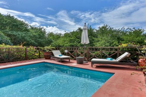 una piscina con 2 tumbonas y una sombrilla en Villa Darcy - Serene 1 bedroom villa in Cap Estate with private pool villa, en Cap Estate