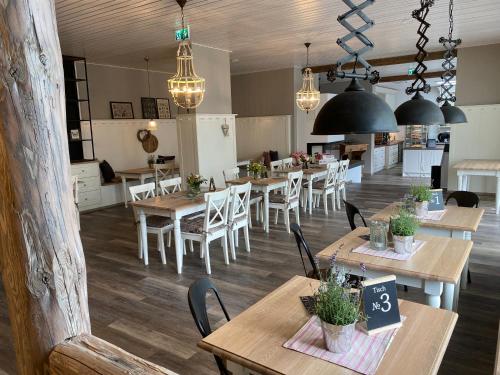 a restaurant with wooden tables and chairs and chandeliers at Café Ilse - Ferienwohnungen in Ranis