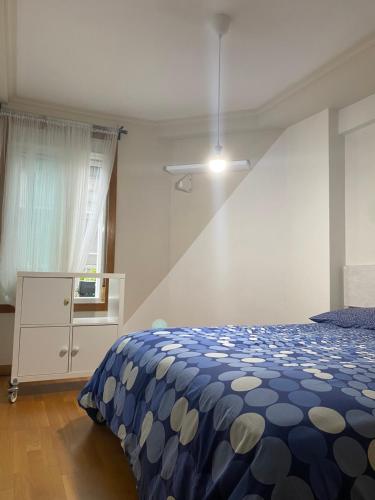 a bedroom with a blue and white bed and a window at Moderno apartamento con encanto en el centro de Vigo in Vigo