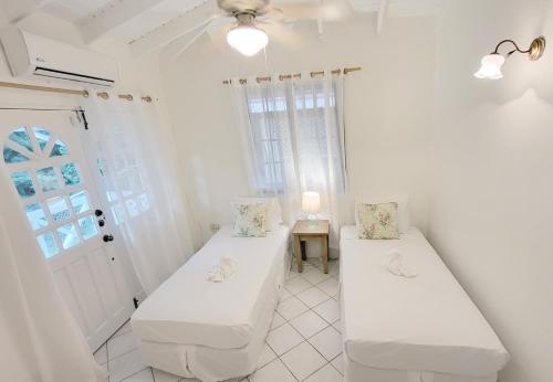 two beds in a white room with a window at The Date House - Four Bedroom Villa with Private Pool near the beach and Calabash Cove Resort villa in Bois dʼOrange