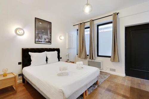 1 dormitorio con 1 cama blanca grande y 2 ventanas en Pick A Flat's Apartment in Place Vendôme/Tuileries - Rue Saint-Honoré, en París