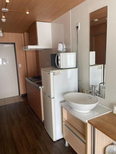 uma cozinha com um frigorífico branco e um lavatório em HOTEL Progress inn 名護 MATABee em Nago